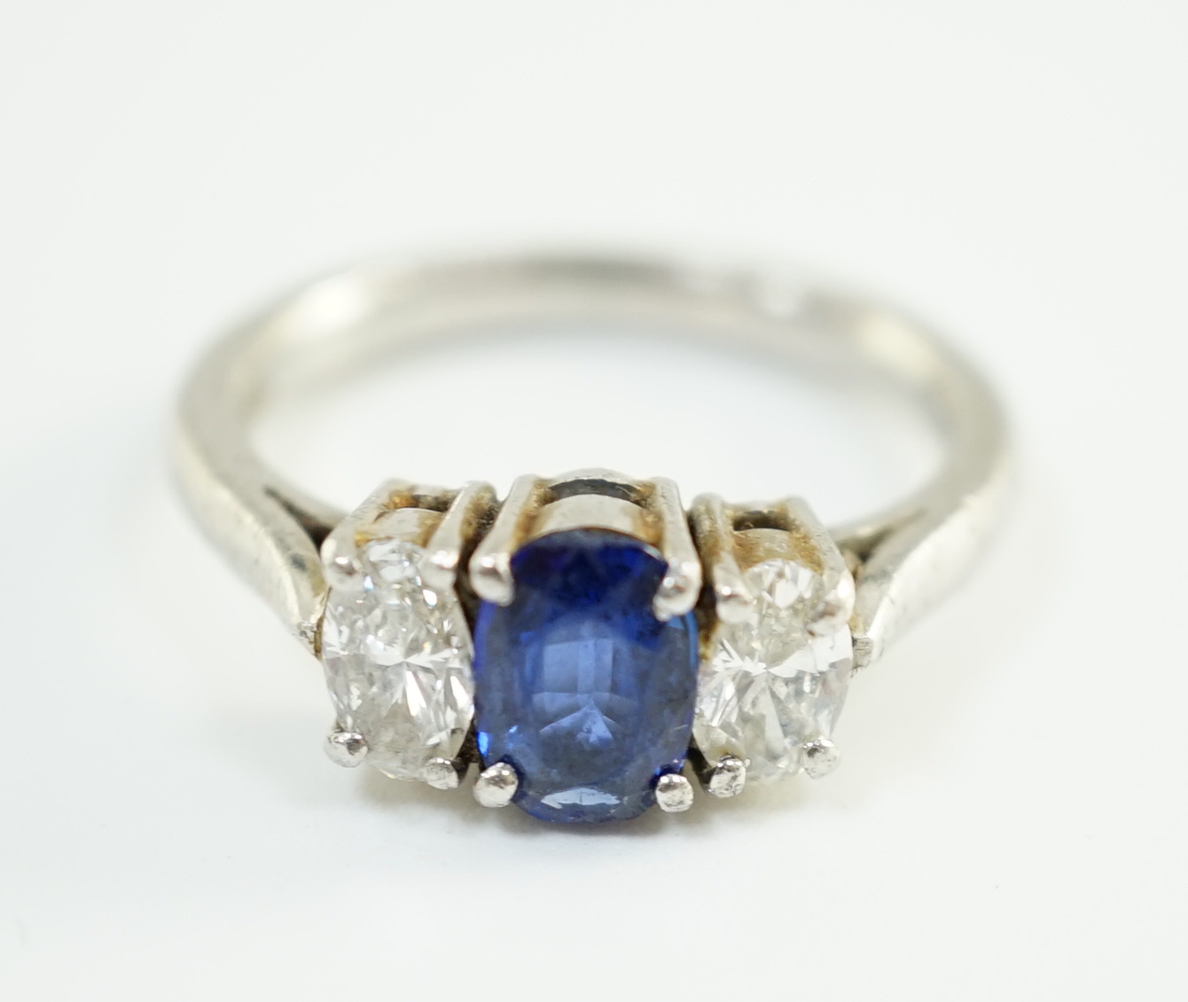 A modern platinum, singe stone oval cut sapphire and two stone oval cut diamond set ring